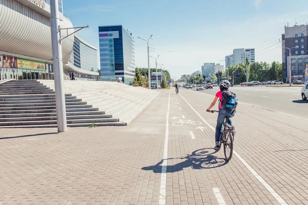 УФА, Россия - МАЙ 2016: женщина-велогонщица едет по велодорожке параллельно улицам с автомобилями. Концепция городского транспорта и движения — стоковое фото