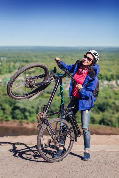 Junge Radfahrerin hält ihr Fahrrad glücklich lächelnd in die Höhe — Stockfoto