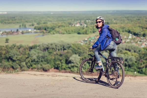 Nachdenkliche junge Frau mit Helm radelt im Wald — Stockfoto