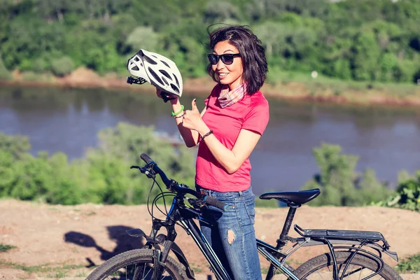 Bike helmet - woman putting biking helmet on during bicycle ride