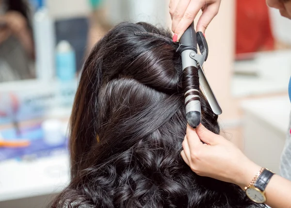 Stylistka v kadeřnictví salon pomocí kulmy bruneta vlasy měna — Stock fotografie