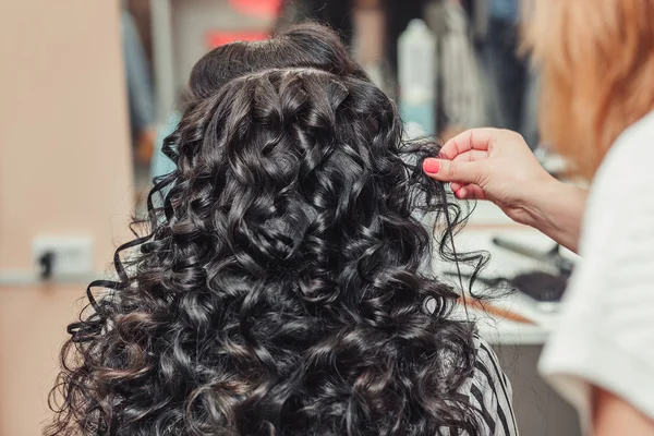 Barber hand holding the brunette curls at the hairdresser salon — Stock Photo, Image