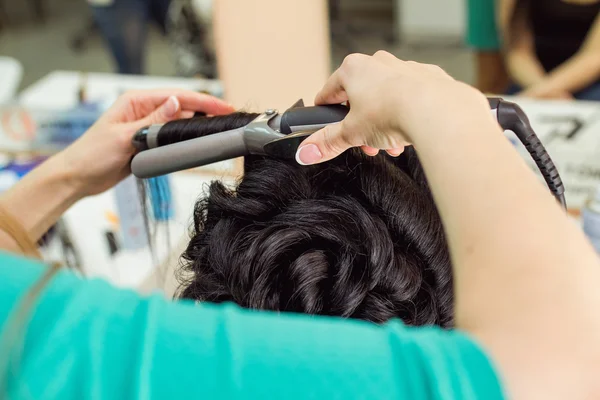 Close up da mão do estilista usando ferro de ondulação para cachos de cabelo — Fotografia de Stock