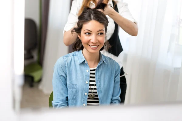 Professional hairstylist doing hairstyle to a brunette smiley gi — Stock Photo, Image