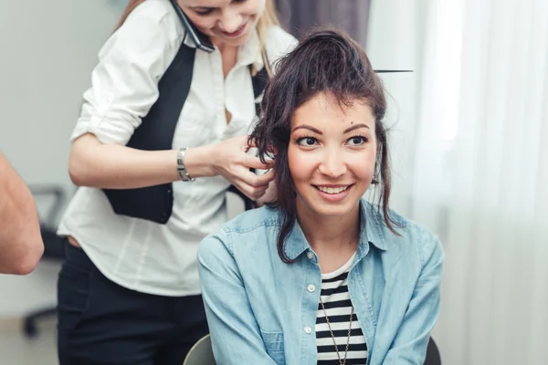 Peluquero profesional haciendo peinado a una chica sonriente morena en el salón de belleza — Foto de Stock