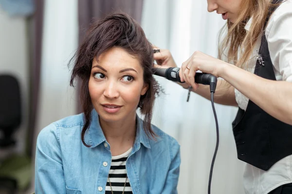 Professional hairdresser doing hairstyle to young woman on the b — Stock Photo, Image