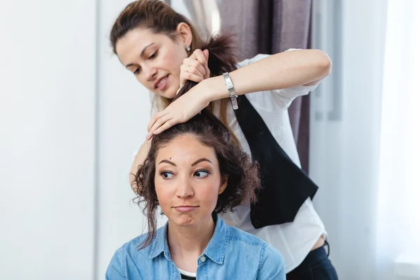 Hair stylist making ringlets to a happy brunette woman. Hairdres — Stock Photo, Image