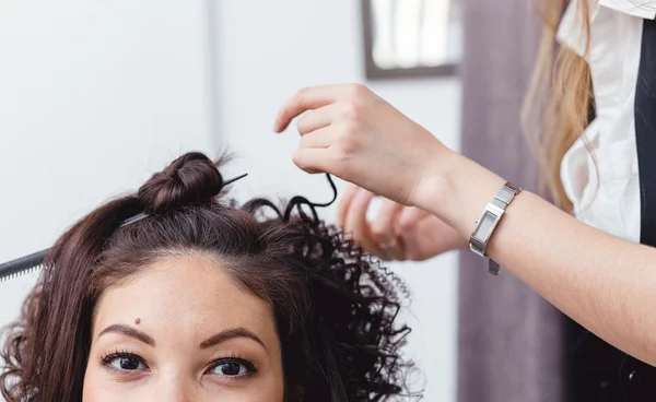 Gros plan d'une femme coiffeuse faisant des boucles à de longs cheveux bruns — Photo