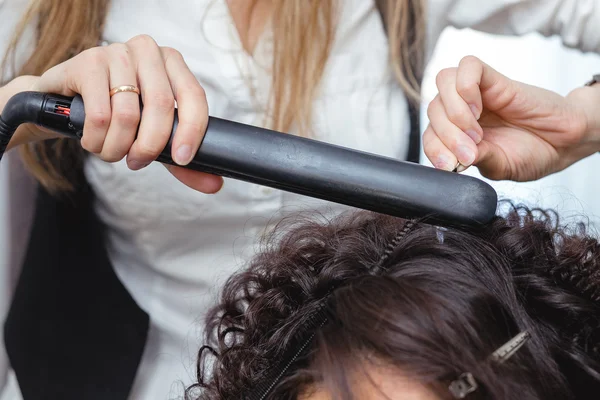 Gros plan d'une femme coiffeuse faisant des boucles à de longs cheveux bruns — Photo