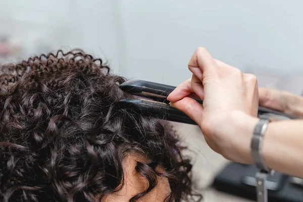 Крупним планом жінка-перукар робить завитки на довге коричневе волосся — стокове фото