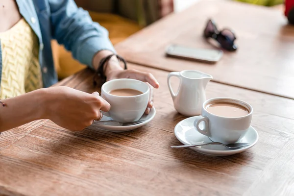 Две чашки кофе с женскими руками на деревянном столе в кафе — стоковое фото