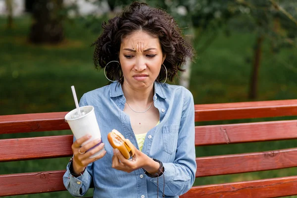 Наружный портрет женщины, смотрящей на гамбургер и дерьмо быстрого питания — стоковое фото