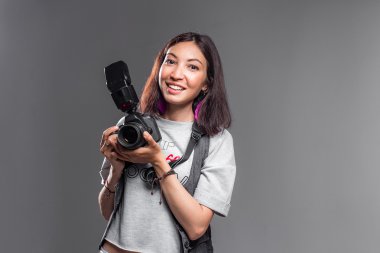 Mutlu genç kadın ile gri bir arka karşı modern dijital fotoğraf makinesi