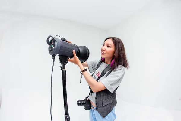 Fotógrafa mujer ajusta el equipo flash, cámara y softbox i — Foto de Stock