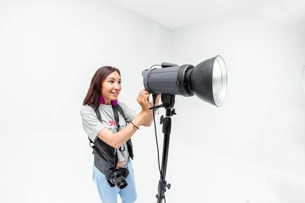 Fotógrafa mujer ajusta el equipo flash, cámara y softbox i — Foto de Stock