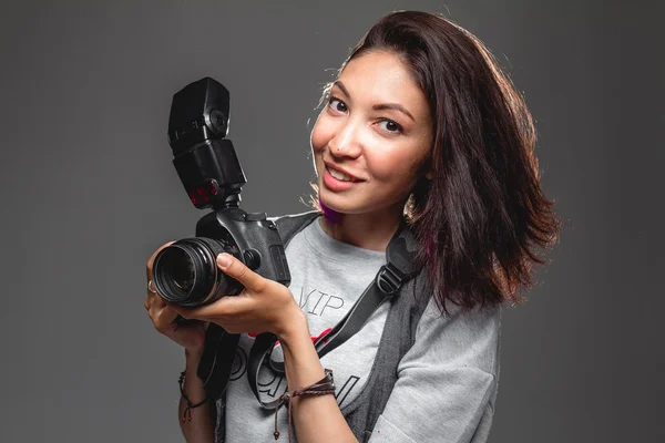 Mujer joven feliz con cámara digital moderna contra una espalda gris —  Fotos de Stock