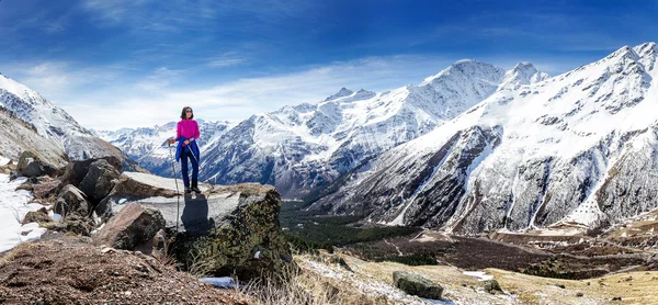 Caminante mujer caminando por sendero de montaña con bastones de senderismo, mirando a la vista en la región de Elbrus, montañas del Cáucaso — Foto de Stock