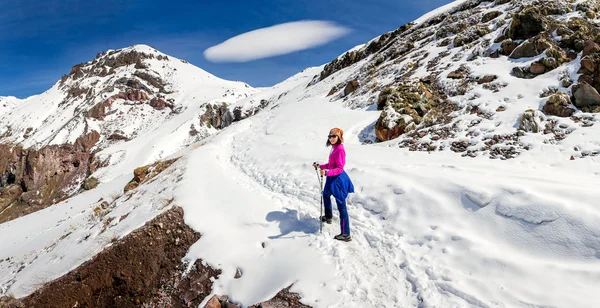 Mujer senderismo en un sendero nevado en las montañas del Cáucaso en el fondo de la nube lenticular inusual — Foto de Stock