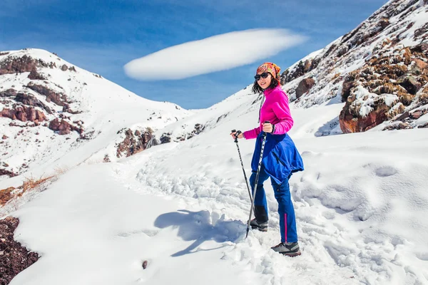 Mujer senderismo en un sendero nevado en las montañas del Cáucaso en el fondo de la nube lenticular inusual — Foto de Stock