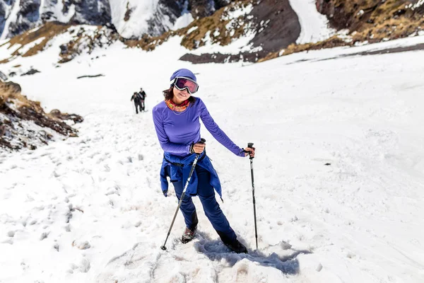 Mulher caminhando no dia ensolarado de inverno na paisagem da montanha. Caminhante feminina em roupas quentes e brilhantes desfrutando trilha caminhada na pista coberta de neve . — Fotografia de Stock
