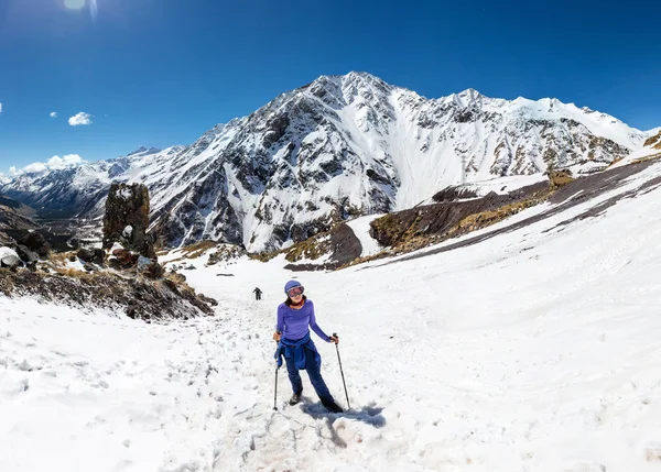 Женщина путешествует в солнечный зимний день в горном ландшафте. Женщина-туристка в теплой яркой одежде наслаждается прогулкой по заснеженной трассе . — стоковое фото