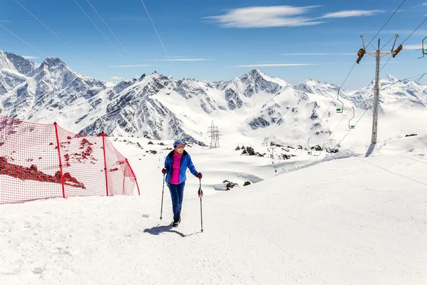 Wanderin an einem sonnigen Wintertag in der Berglandschaft. Wanderin in warmer, heller Kleidung genießt Wanderung auf schneebedeckter Piste. — Stockfoto