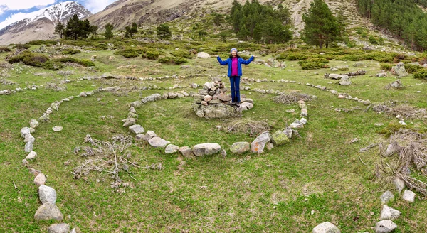 Mujer excursionista de pie en espiral mística esotérica, construida de piedra en un valle de montaña — Foto de Stock