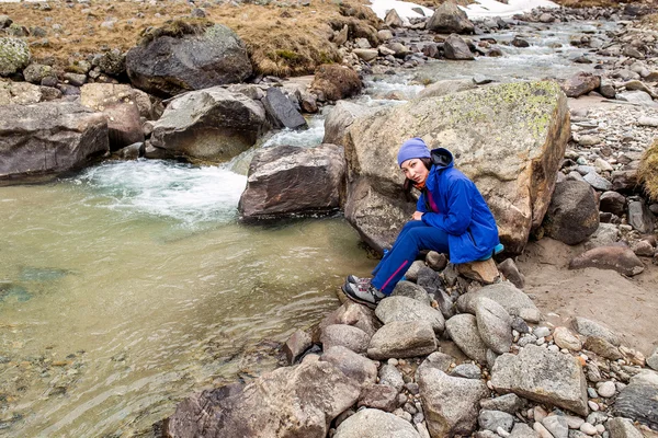 Wandelaar vrouw neemt water uit de rivier in de Zwitserse bergen tijdens een wandelavontuur. — Stockfoto