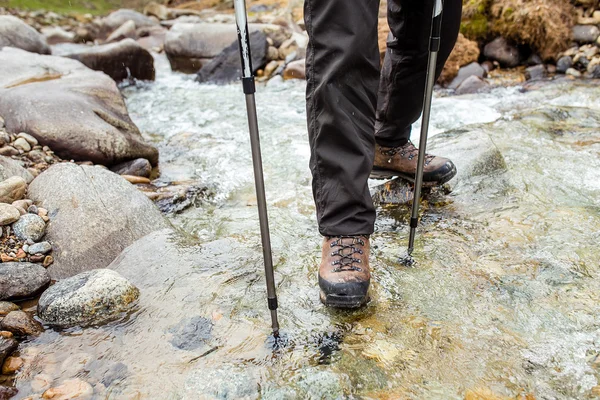 Man i Trekking stövlar vandring utomhus och vada floden eller bäck eith stenar på bakgrunden. Livsstils-, rese-eller överlevnads koncept uppifrån och — Stockfoto