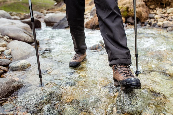 Hombre en botas de trekking senderismo al aire libre y vadeando río o arroyo eith piedras en el fondo. Estilo de vida, Viajes o concepto de supervivencia vista superior — Foto de Stock