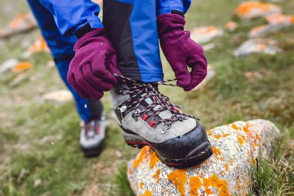 Wandelaar koppelverkoop boot veters op rots, hoog in de bergen — Stockfoto