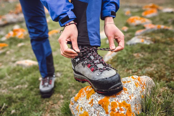 Wandelaar koppelverkoop boot veters op rots, hoog in de bergen — Stockfoto