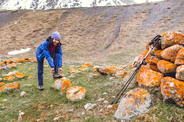 Турист завязывает шнурки на скале, высоко в горах — стоковое фото