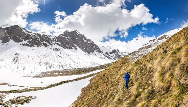 Excursionista turístico caminando en las montañas cerca del campo de nieve y glaciar. Concepto de trekking fuera de temporada — Foto de Stock