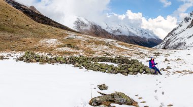 bir kayaya muhteşem dağlarda oturan genç kadın