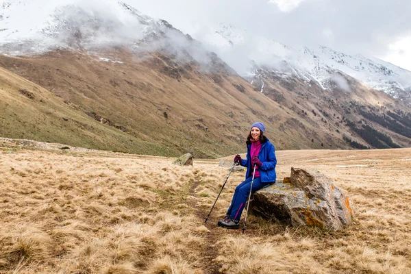 Mladá žena, sedící na skále v nádherné hory — Stock fotografie