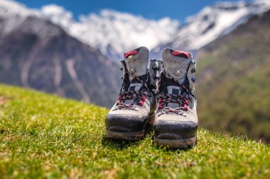 Old hiking shoes and Alpine landscape at background clipart