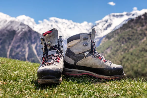 Velhos sapatos de caminhada e paisagem alpina no fundo — Fotografia de Stock