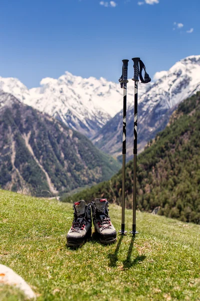 Botas de caminhada com postes de trekking na grama na montanha nevado Cáucaso gama fundo — Fotografia de Stock