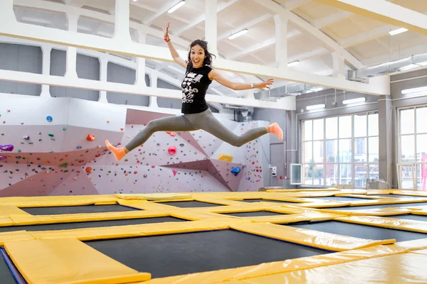 Jumping young and funny woman on a trampoline in fitness centre — Stock Photo, Image