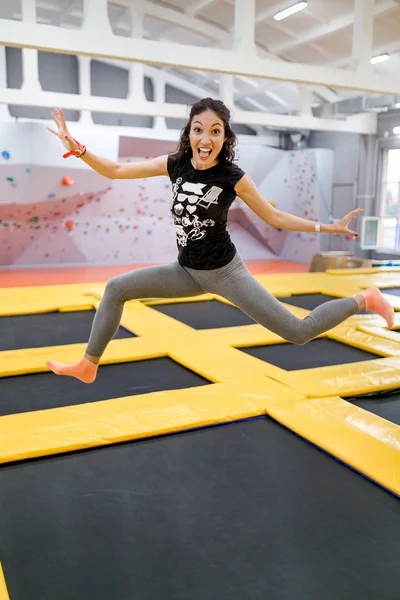 Jumping young and funny woman on a trampoline in fitness centre