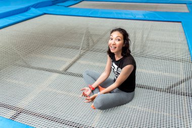 Çekici genç kadın oturdu üstünde A büyük trambolin