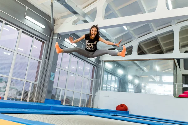Twine jumping jovem mulher no o trampolim — Fotografia de Stock