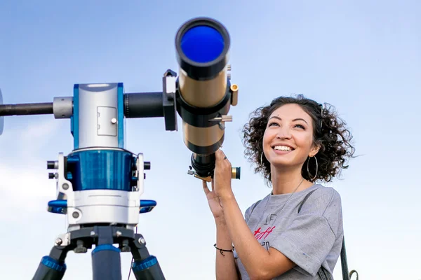 Girl looking through a telescope outdoors — Stock Photo, Image