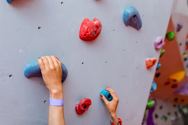 Escalador joven mujer comenzando bouldering pista en artificial pared interior, manos de cerca — Foto de Stock