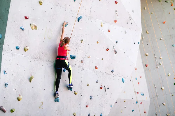Активна молода жінка на скельній стіні в спортивному центрі — стокове фото