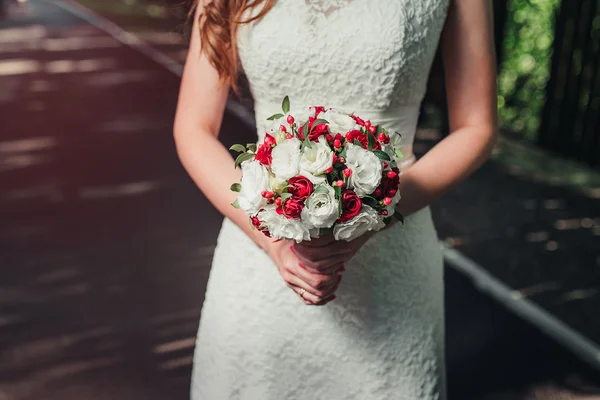 Bride holding beautiful red wedding flowers bouquet — Stock Photo, Image