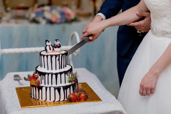 Feliz casal elegante casados cuting bolo bonito em um restaurante, comemorando casamento — Fotografia de Stock