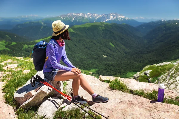 Mulher jovem irreconhecível sentada em uma rocha com mochila e olhando para o horizonte — Fotografia de Stock