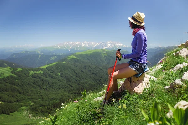 Mujer joven irreconocible sentada en una roca con mochila y mirando al horizonte —  Fotos de Stock